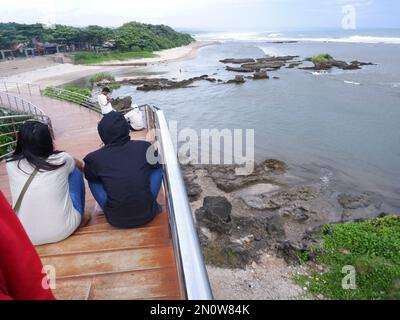 Garut, Indonesien - Dezember 12,2022: Leute, die auf der Straße oder Brücke sitzen oder sich entspannen oder Holztreppen am Strand, Blick auf den Strand Stockfoto