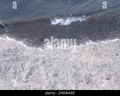 Die Felsen an der Küste werden in eine Straße zwischen dem Meer und dem Fluss, dem Hafen, dem Strand und dem Himmelblau gestapelt Stockfoto