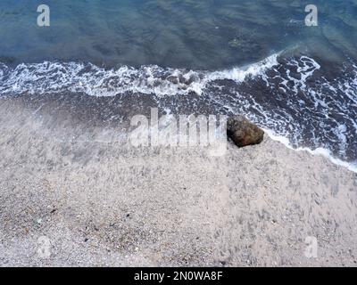 Die Felsen an der Küste werden in eine Straße zwischen dem Meer und dem Fluss, dem Hafen, dem Strand und dem Himmelblau gestapelt Stockfoto