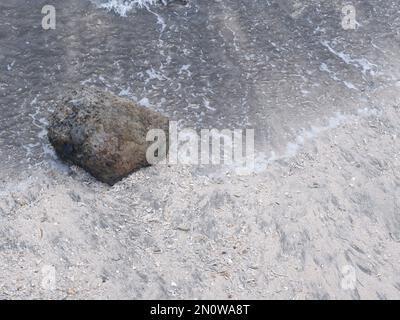 Die Felsen an der Küste werden in eine Straße zwischen dem Meer und dem Fluss, dem Hafen, dem Strand und dem Himmelblau gestapelt Stockfoto