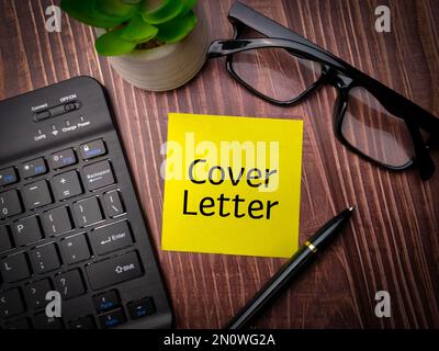 Tastatur, Stift und Brille mit dem Wort Anschreiben auf Holztisch. Stockfoto