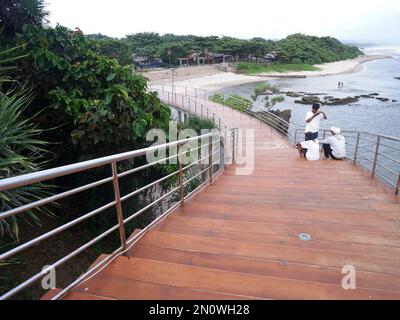 Garut, Indonesien - Dezember 12,2022: Leute, die auf der Straße oder Brücke sitzen oder sich entspannen oder Holztreppen am Strand, Blick auf den Strand Stockfoto