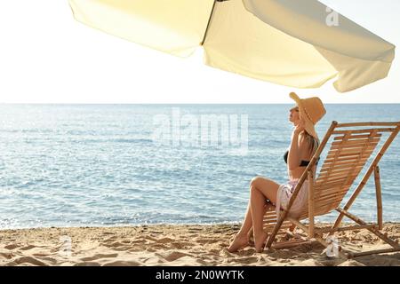 Eine Frau, die sich auf einem Liegestuhl am Sandstrand entspannt. Sommerferien Stockfoto