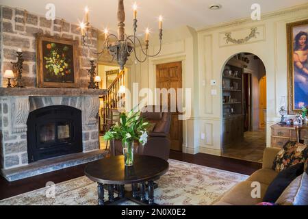 Grauer Natursteinkamin und runder hölzerner Couchtisch im Wohnzimmer im Haus im Renaissance-Stil. Stockfoto