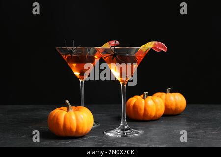 Dekorierte Gläser mit Getränken auf einem grauen Tisch. Halloween-Feier Stockfoto