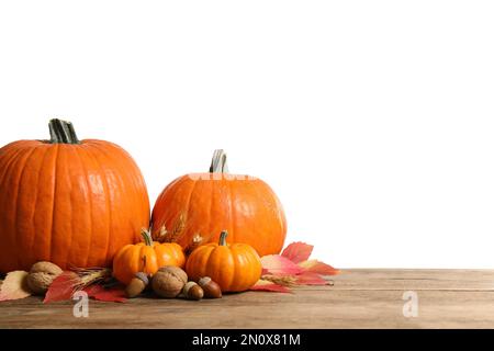 Zusammensetzung mit reifen Kürbissen und Herbstblättern auf Holztisch vor weißem Hintergrund. Frohes Thanksgiving Stockfoto