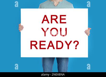 Mann mit Poster und Text sind Sie bereit? Auf blauem Hintergrund, Nahaufnahme Stockfoto