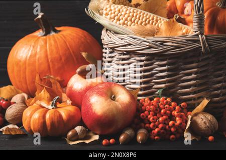 Zusammensetzung mit Gemüse, Obst und Herbstblättern auf schwarzem Holztisch. Thanksgiving-Tag Stockfoto