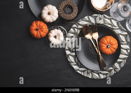 Herbsttisch mit goldenem Besteck und Kürbissen auf schwarzem Hintergrund, flach liegend. Platz für Text Stockfoto