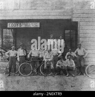 Authentische Vintage-Fotografie aus den 1890er Jahren von amerikanischen Arbeitern im ländlichen Raum mit Fahrrädern bei Eddy’s Rough & Ready Steel Plows – Historisches Schwarzweiß-Gruppenporträt aus der Zeit des Fahrradbooms im Mittleren Westen, Ende des 19. Jahrhunderts landwirtschaftliche Ausrüstung Business Setting Stockfoto