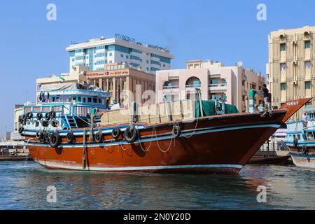 Dubai, Vereinigte Arabische Emirate - 14,2022. Februar: Dubai Creek mit hölzernen Booten, die auf dem ruhigen Wasser unter einem klaren blauen Himmel treiben. Eine ruhige Szene vermittelt ein Gefühl von Stockfoto