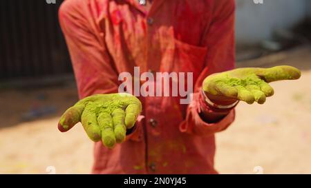 indisches kleines Mädchen mit bunten Palmen und hupi mit Farbspritzer Stockfoto