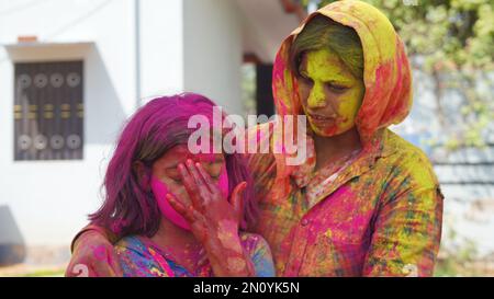 Außenansicht der asiatischen, indischen glücklichen Mutter, Tochter in indischer Kleidung, die das Holi Festival feiert, zusammen mit Farbpulver. Stockfoto