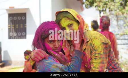 Außenansicht der asiatischen, indischen glücklichen Mutter, Tochter in indischer Kleidung, die das Holi Festival feiert, zusammen mit Farbpulver. Stockfoto