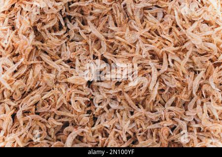 Jede Menge trockene Garnelen im Hintergrund zum Verkauf. Nahaufnahmen mit Pfahlstruktur in leuchtend hellrosa, blassen Farbtönen Stockfoto