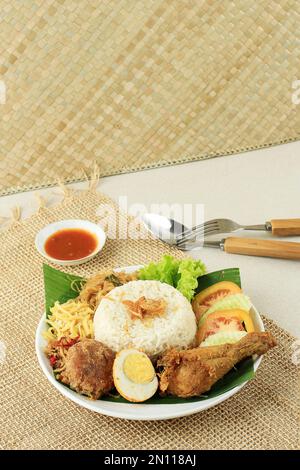 Nasi Uduk oder Nasi Lemak, gedünsteter Reis mit verschiedenen Beilagen, Huhn, Tempeh, Eier, Kartoffelfritter. Indonesische und malaysische Traditioanl Food Stockfoto