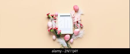 Festliche Komposition mit leerem Bilderrahmen, bemalten Ostereiern, Häschen und Blumen auf hellem Hintergrund Stockfoto