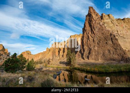 Rote Felswände in der Morgensonne, reflektiert im Fluss, Kurs des Crooked River, Canyon mit Felsformationen, die Rote Mauer, Smith Rock State Pa Stockfoto