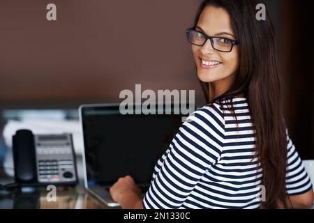 Ich mache Geschäfte von zu Hause aus. Porträt einer erfolgreichen jungen Geschäftsfrau, die zu Hause an ihrem Schreibtisch sitzt. Stockfoto