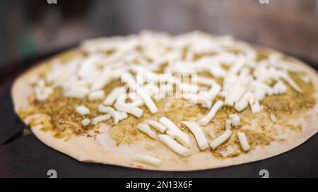 Toasten von Käse-Quesadillas auf einer heißen Grillaufnahme aus nächster Nähe. Käse und würzige Paste als Belag für die Tortilla. Stockfoto