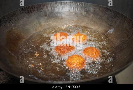 Frittieren Sie Falafel-Bälle in einem Wok, heiße Speiseöle sprudeln, und Falafel-Bälle werden goldbraun. Stockfoto