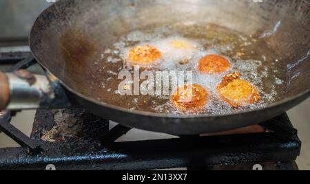 Frittieren von Falafel-Bällen im Wok, Sprudeln von heißen Speiseölen und goldbraune Falafel-Bälle Stockfoto