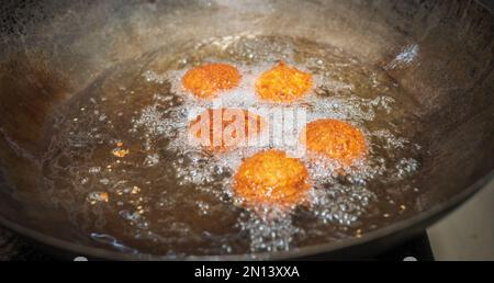 Frittieren von Falafel-Bällen im Wok, Sprudeln von heißen Speiseölen und goldbraune Falafel-Bälle Stockfoto