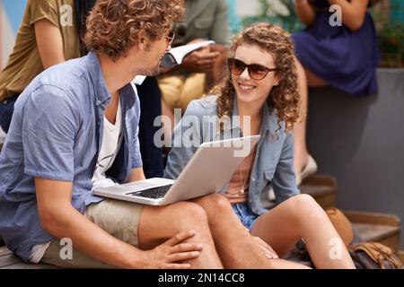 Chillen auf dem Campus zwischen den Klassen. Eine Aufnahme von Studenten, die auf dem Campus einen Laptop teilen. Stockfoto