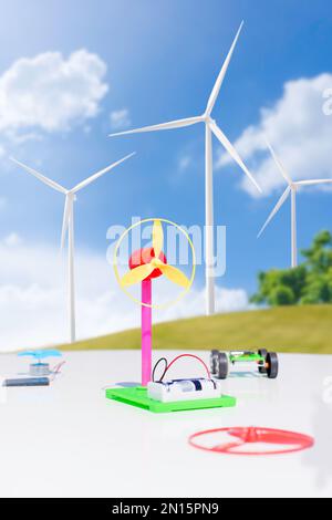 Eine simulierte elektrische Turbine für das Lernen von Kindern wird auf einem weißen Tisch platziert. Dahinter befindet sich ein Feld mit Windmühlen. Stockfoto