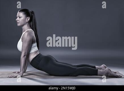 Einfarbig wie eine Trainerin in Yoga-Taubenposition (Kapotasana) Stockfoto