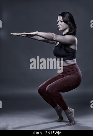 Monochrom-Ton einer Yoga-Praktizierenden Frau in Utkatasana (Stuhl)-Pose Stockfoto