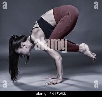 Einfarbig, wie eine Yoga-Trainerin Kakasana macht (Krähenhaltung) Stockfoto