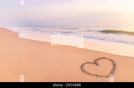 Zeichnen Sie morgens am Sandstrand eine Herzform. Um das Valentinstag-Festival zu begrüßen. Stockfoto