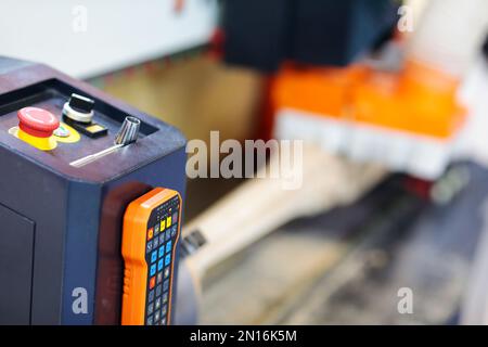 Bedientafel und Fernsteuerung der holzbearbeitenden CNC-Fräsmaschine. Selektiver Fokus. Stockfoto