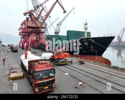 LIANYUNGANG, CHINA - 6. FEBRUAR 2023 - Luftbild aufgenommen am 6. Februar 2023 zeigt Arbeiter, die Dünger für den Frühjahrsanbau am Liegeplatz von P entladen Stockfoto