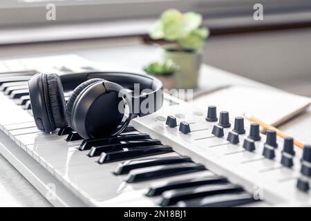Nahaufnahme, Kopfhörer auf MIDI-Tastatur, Musikkonzept. Stockfoto