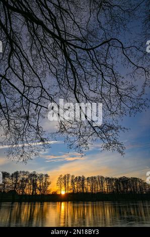 Lietzen, Deutschland. 05. Februar 2023. Der Sonnenuntergang scheint farbenfroh über einem kleinen See im Osten Brandenburgs und spiegelt sich im Eis auf dem Wasser wider. Zu Beginn der Woche erwarten in Berlin und Brandenburg niedrige Temperaturen und vereiste Bedingungen in einigen Gegenden. Wie der deutsche Wetterdienst (DWD) am Montag angekündigt hat, beginnt die Woche mit leichtem Schneefall in Teilen von Berlin und Brandenburg. D Kredit: Patrick Pleul/dpa/Alamy Live News Stockfoto