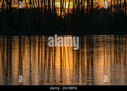 Lietzen, Deutschland. 05. Februar 2023. Der Sonnenuntergang scheint farbenfroh über einem kleinen See im Osten Brandenburgs und spiegelt sich im Eis auf dem Wasser wider. Zu Beginn der Woche erwarten in Berlin und Brandenburg niedrige Temperaturen und vereiste Bedingungen in einigen Gegenden. Wie der deutsche Wetterdienst (DWD) am Montag angekündigt hat, beginnt die Woche mit leichtem Schneefall in Teilen von Berlin und Brandenburg. D Kredit: Patrick Pleul/dpa/Alamy Live News Stockfoto