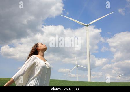 Eine Frau, die frische Luft atmet, in der Nähe einer Windfarm Stockfoto