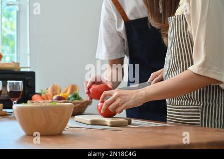 Gekürzte Aufnahme eines jungen Paares, das in der modernen Küche gesundes Essen zubereitet, Freizeit zu Hause genießt Stockfoto