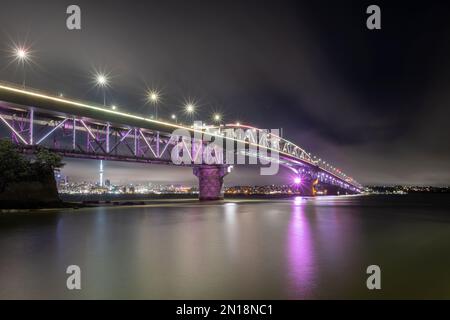 Die Auckland Harbour Bridge leuchtet lila. Auckland, Neuseeland Stockfoto