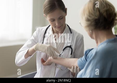 Fokussierte Krankenschwester, die die Vene eines älteren Patienten spritzt Stockfoto