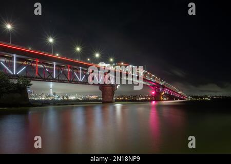 Die Auckland Harbour Bridge leuchtet rot. Auckland, Neuseeland Stockfoto