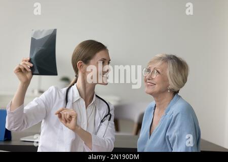 Glückliche Ärztin, die dem älteren Patienten Röntgenaufnahmen zeigt Stockfoto