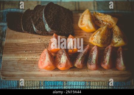 Nahaufnahme von geschnittenem Roggenbrot und scharfen Tomatenstücken Konzeptfoto Stockfoto