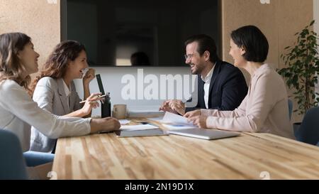 Fröhliche, inspirierte Geschäftskollegen sitzen am Konferenztisch Stockfoto