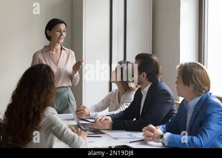 Reife weibliche Chefin, die mit Mitarbeitern in einer Bürobesprechung spricht Stockfoto