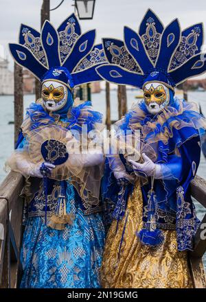 Menschen, die während des Karnevals in Venedig aufwendige und farbenfrohe Masken trugen Stockfoto