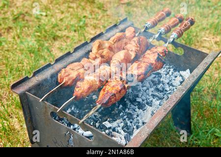 Schweinespieße brazier Feuer Glut Spieße Essen Feiertagsessen Kochen im Freien aus der Nähe Holzkohlegrill mit Feuer Appetitzügler schmackhaft gesund Stockfoto