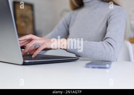 Junge Frau, die zu Hause Code auf einem modernen Laptop eingibt. Weibliche Programmiererin, die online arbeitet Stockfoto